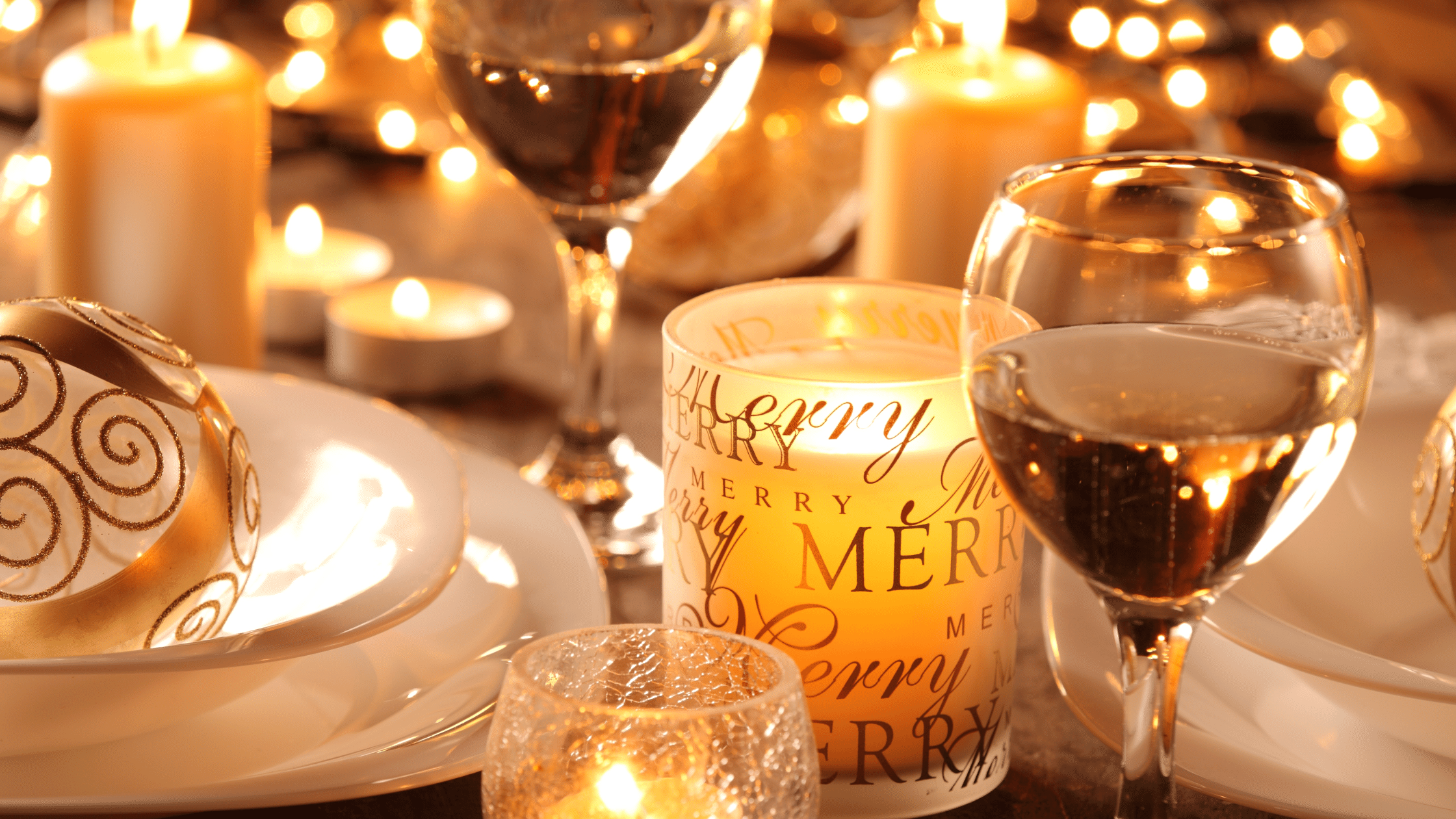 Christmas table set with candles, white wine, and finery.